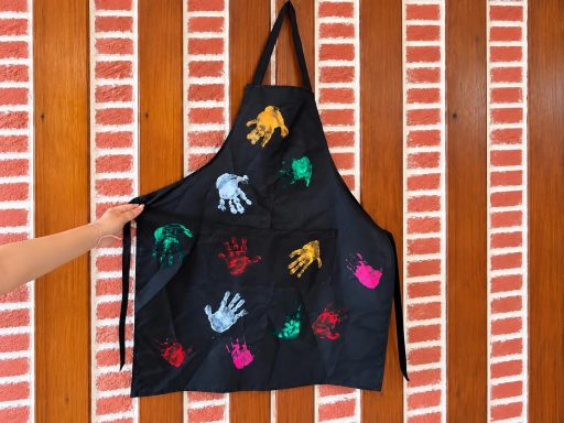 Un tablier plein de petites mains 🎨 Tablier noir décoré avec des empreintes de mains colorées réalisées par des enfants
